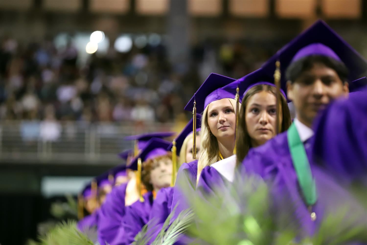 Row of GISH graduates in regalia sitting at Graduation ceremony and looking ahead.